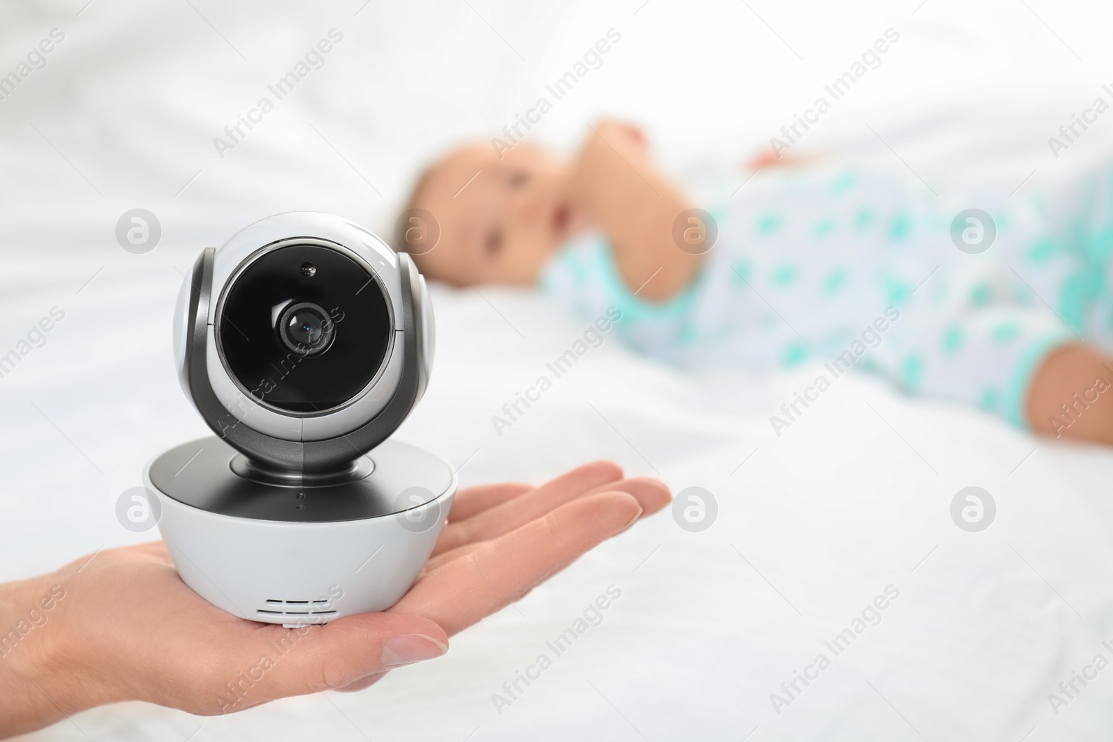 Photo of Woman holding baby camera near child on bed. Video nanny