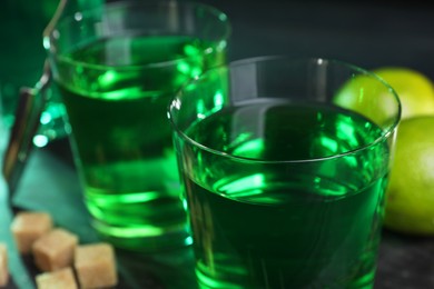 Absinthe in glasses, brown sugar and lime on table, closeup. Alcoholic drink