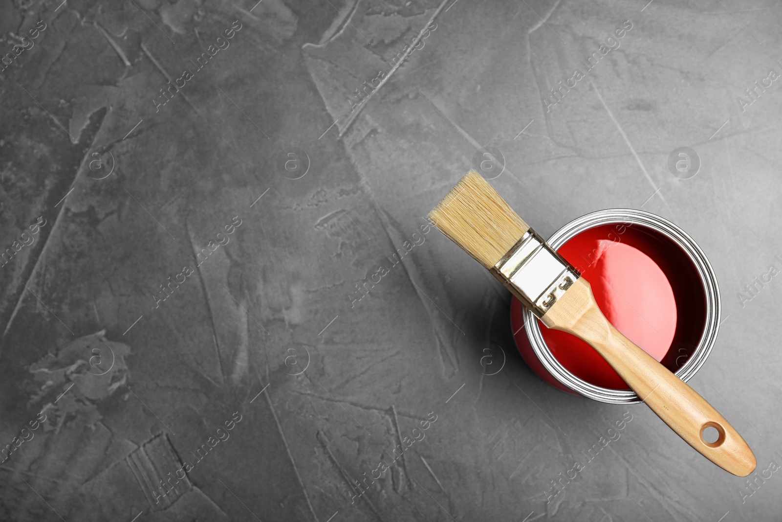 Photo of Can with red paint and brush on gray background, top view. Space for text