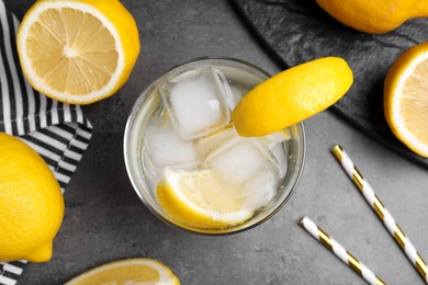 Photo of Soda water with lemon slices and ice cubes on grey table, flat lay