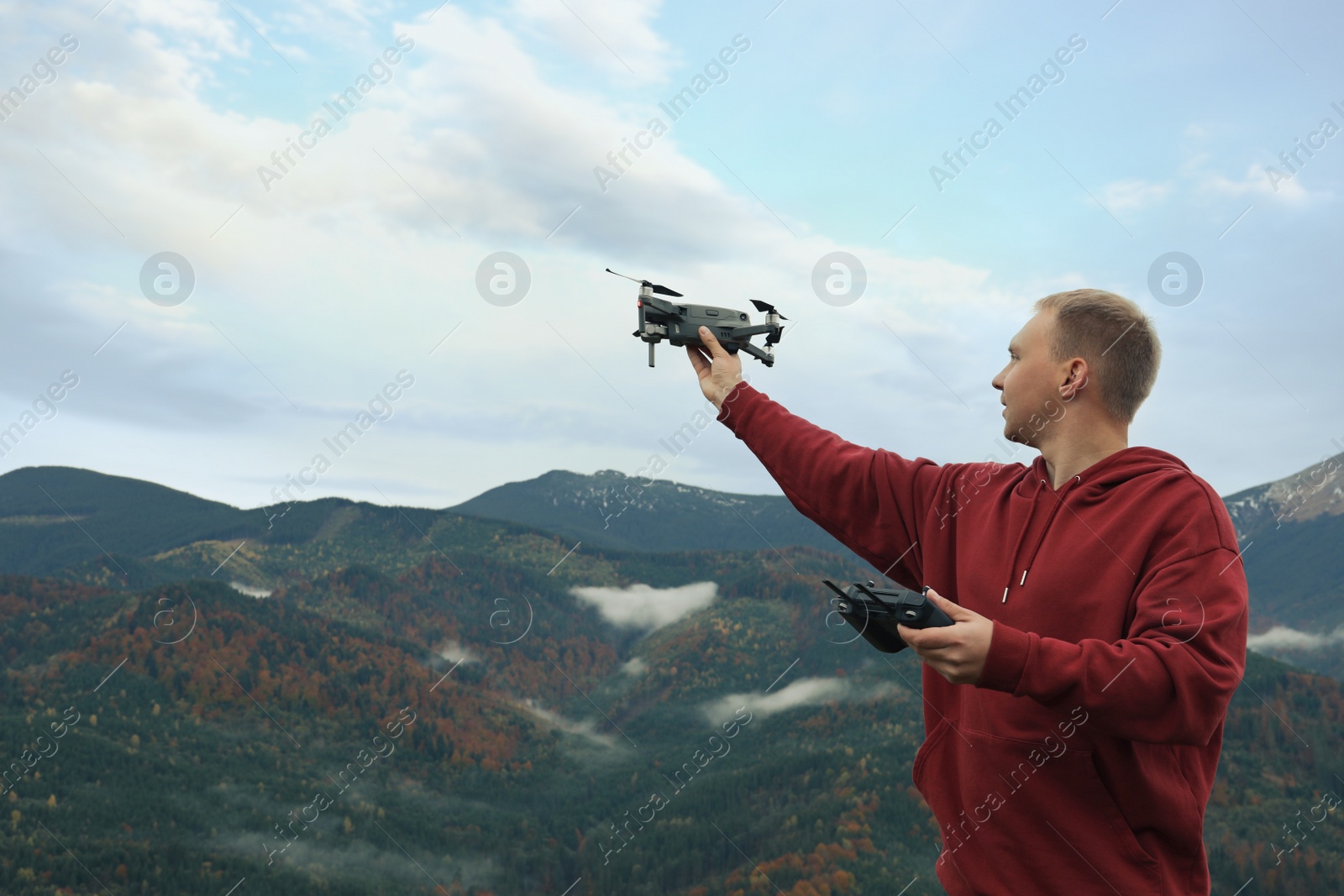 Photo of Young man with modern drone in mountains, space for text