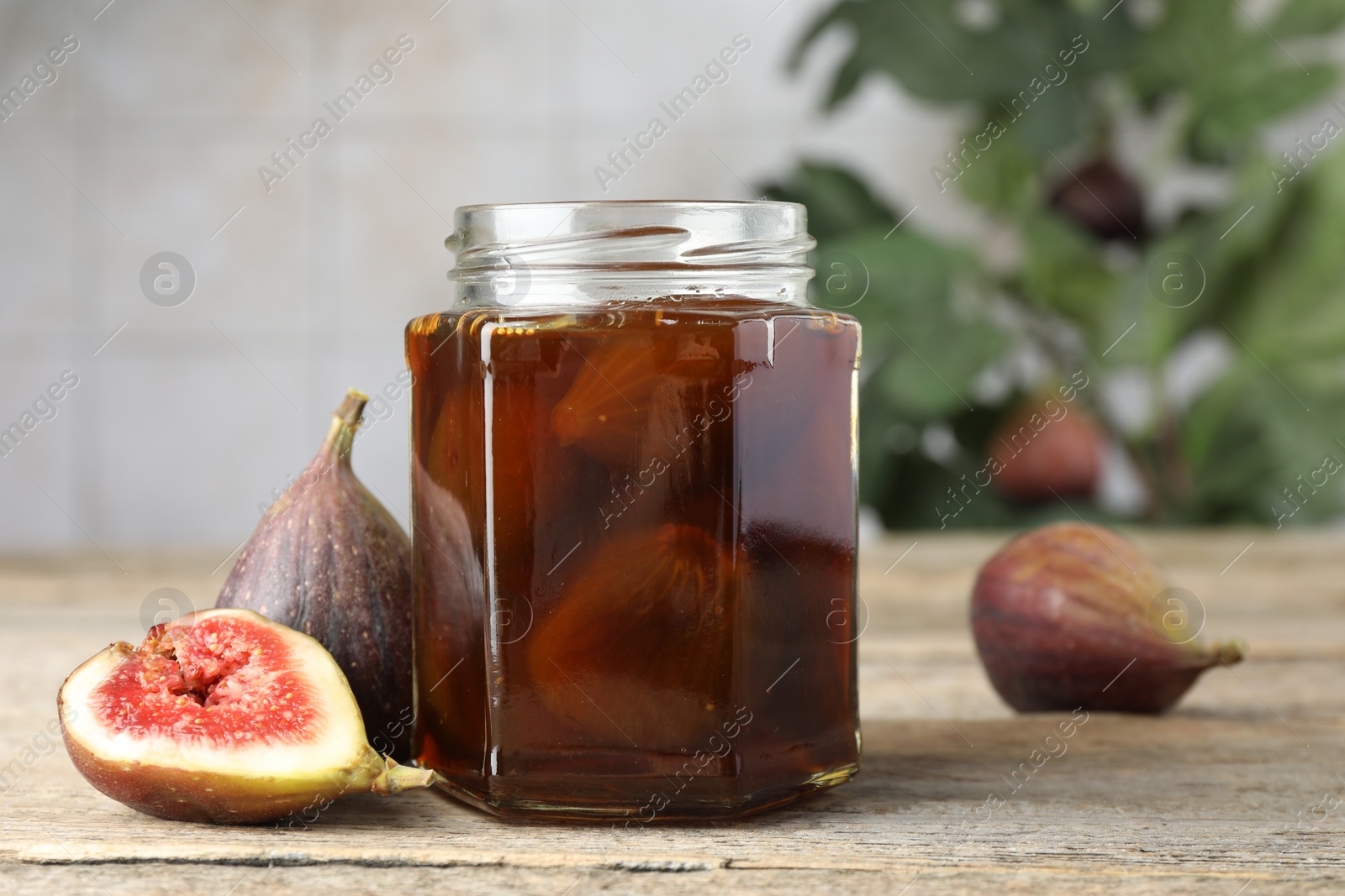 Photo of Jar of tasty sweet jam and fresh figs on wooden table