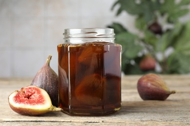 Jar of tasty sweet jam and fresh figs on wooden table