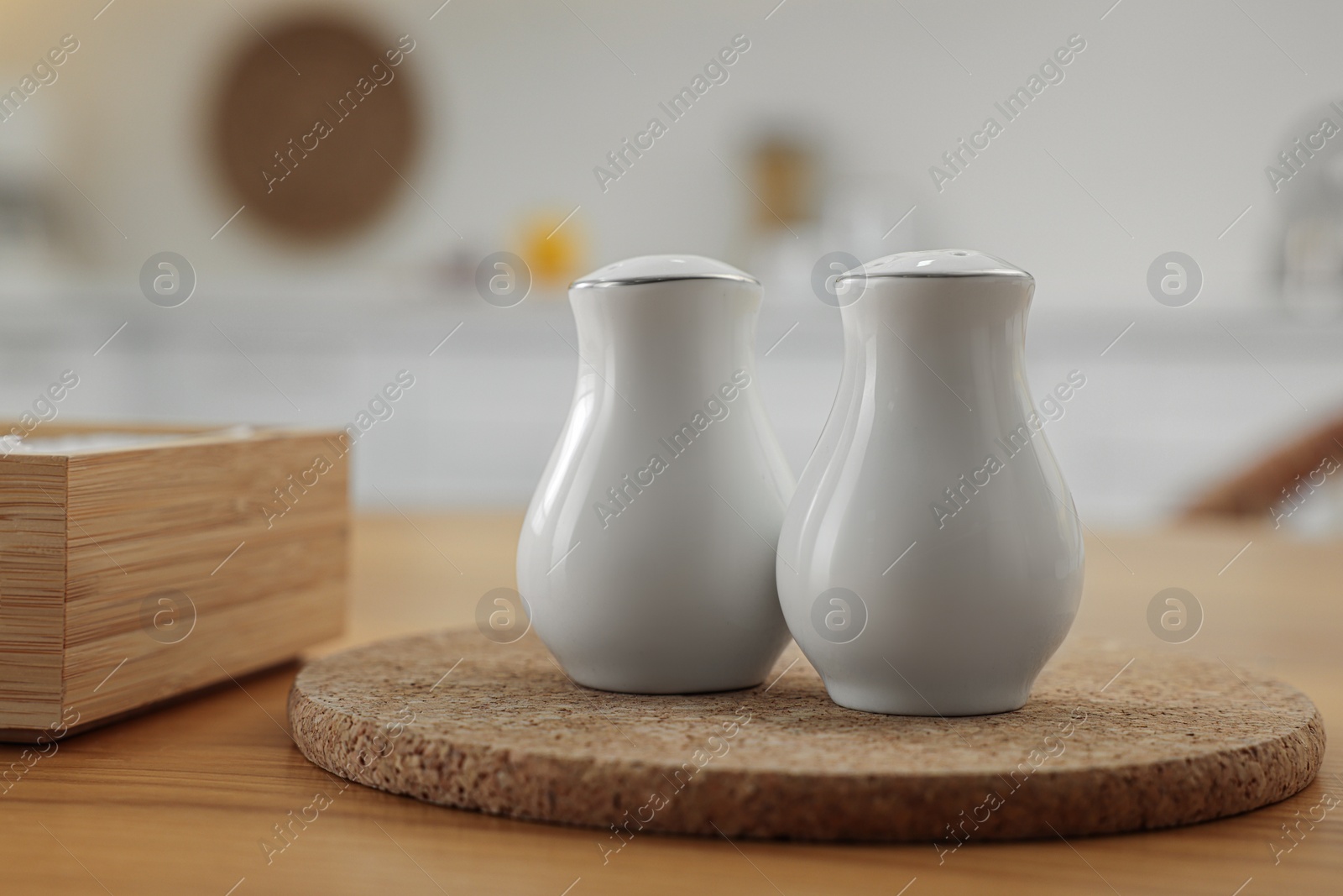 Photo of White ceramic salt and pepper shakers on wooden table indoors