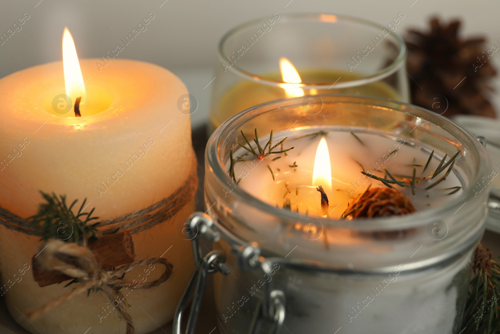 Photo of Burning scented conifer candles on table, closeup view