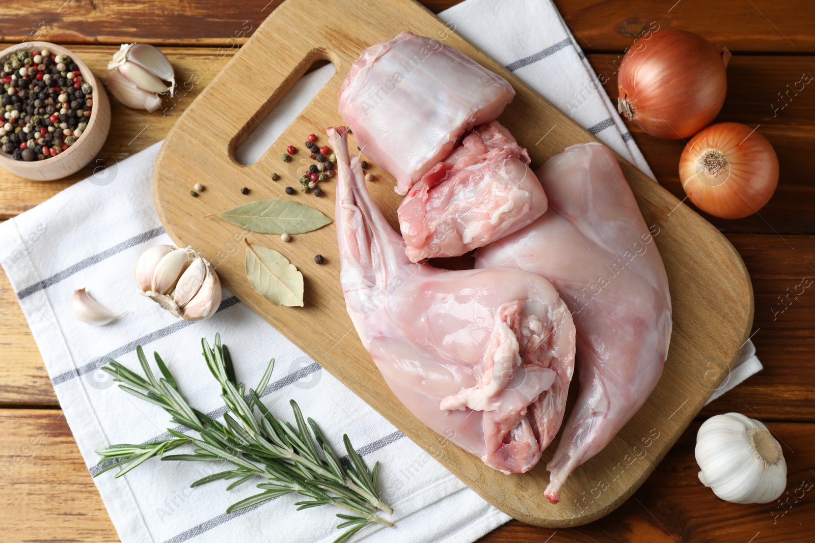 Photo of Fresh raw rabbit meat and spices on wooden table, flat lay