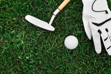 Photo of Golf club, ball and glove on green grass, flat lay