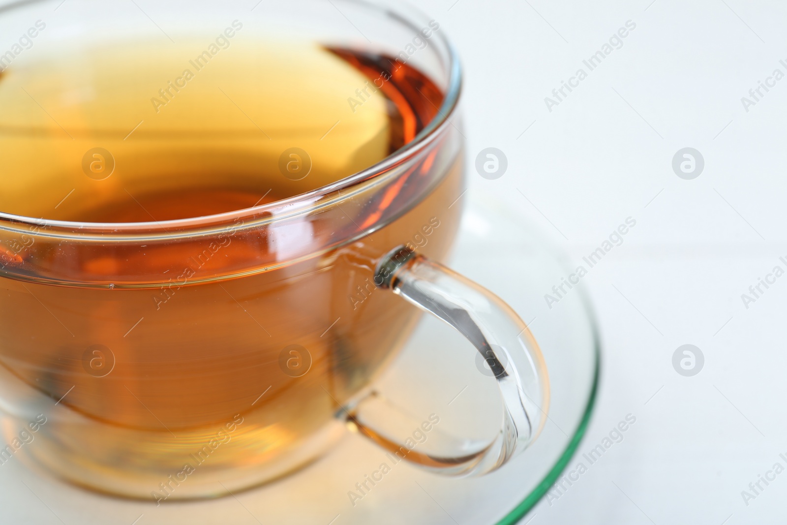 Photo of Glass cup of tea on white table, closeup