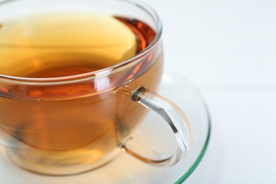 Photo of Glass cup of tea on white table, closeup