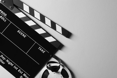 Clapperboard and film reel on grey background, flat lay. Space for text