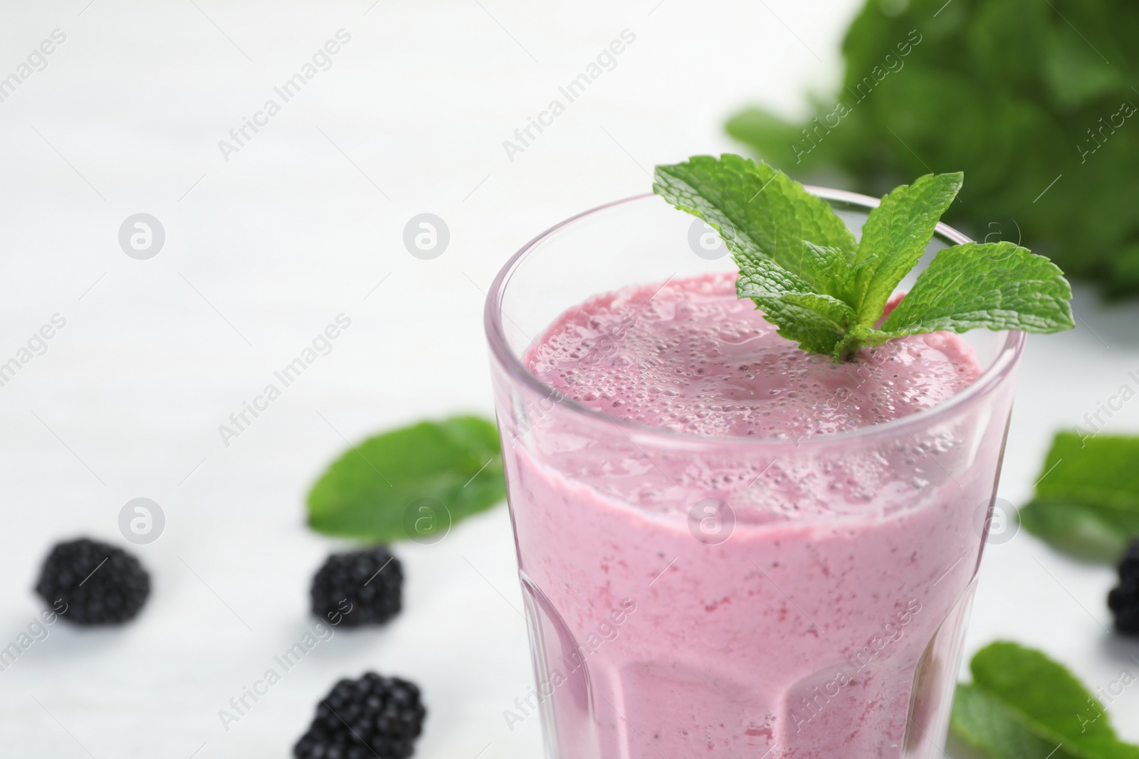 Photo of Glass with tasty blackberry yogurt smoothie on table, closeup