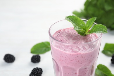 Photo of Glass with tasty blackberry yogurt smoothie on table, closeup