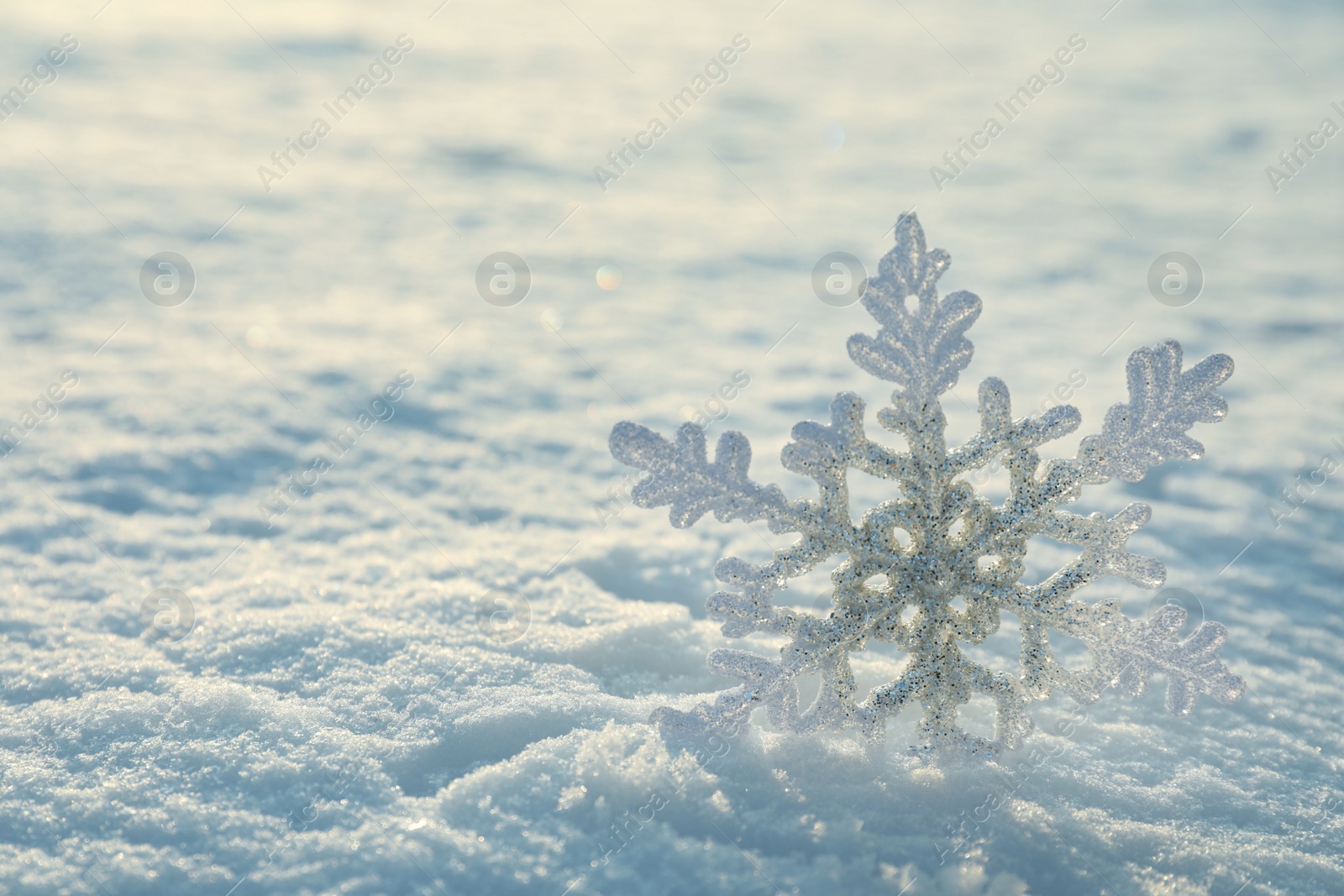 Photo of Beautiful decorative snowflake in white snow, outdoors. Space for text