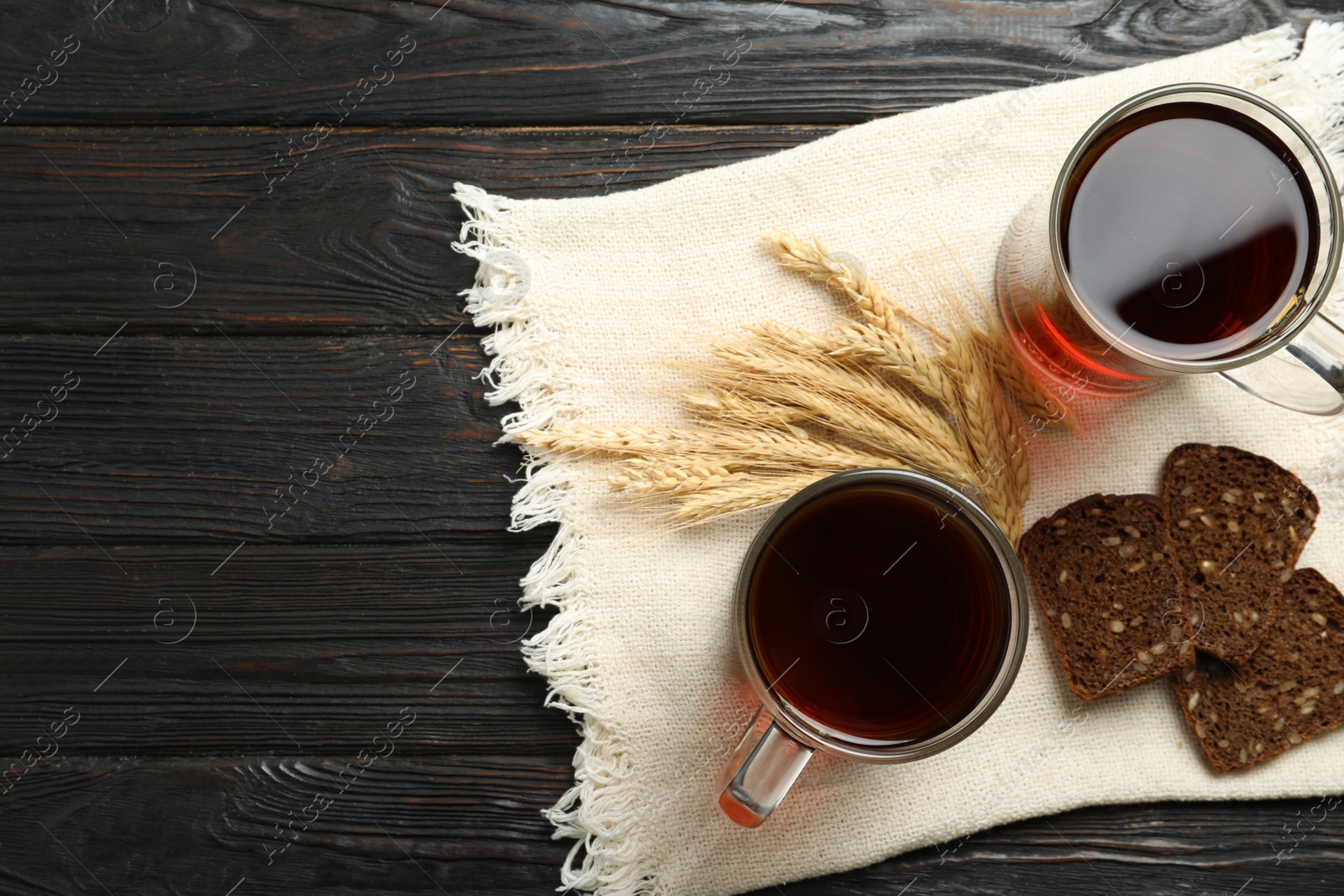 Photo of Flat lay composition with delicious kvass, spikes and bread on wooden table, space for text