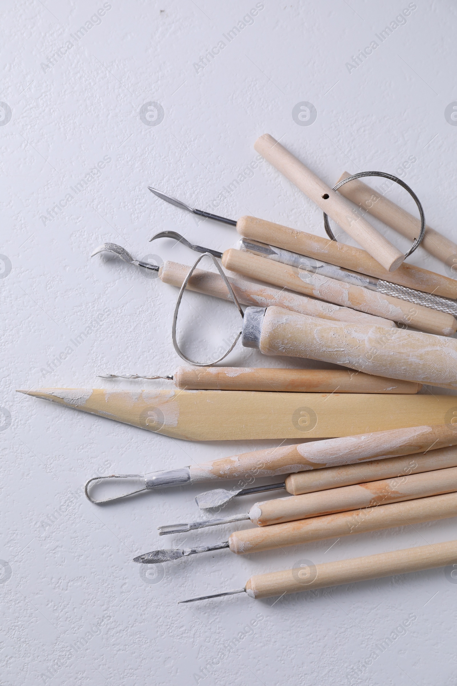 Photo of Set of different clay crafting tools on white table, top view