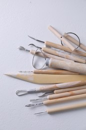 Set of different clay crafting tools on white table, top view