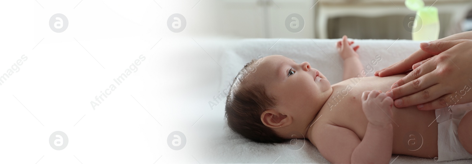 Image of Mother massaging her cute baby with oil indoors, closeup. Banner design with space for text