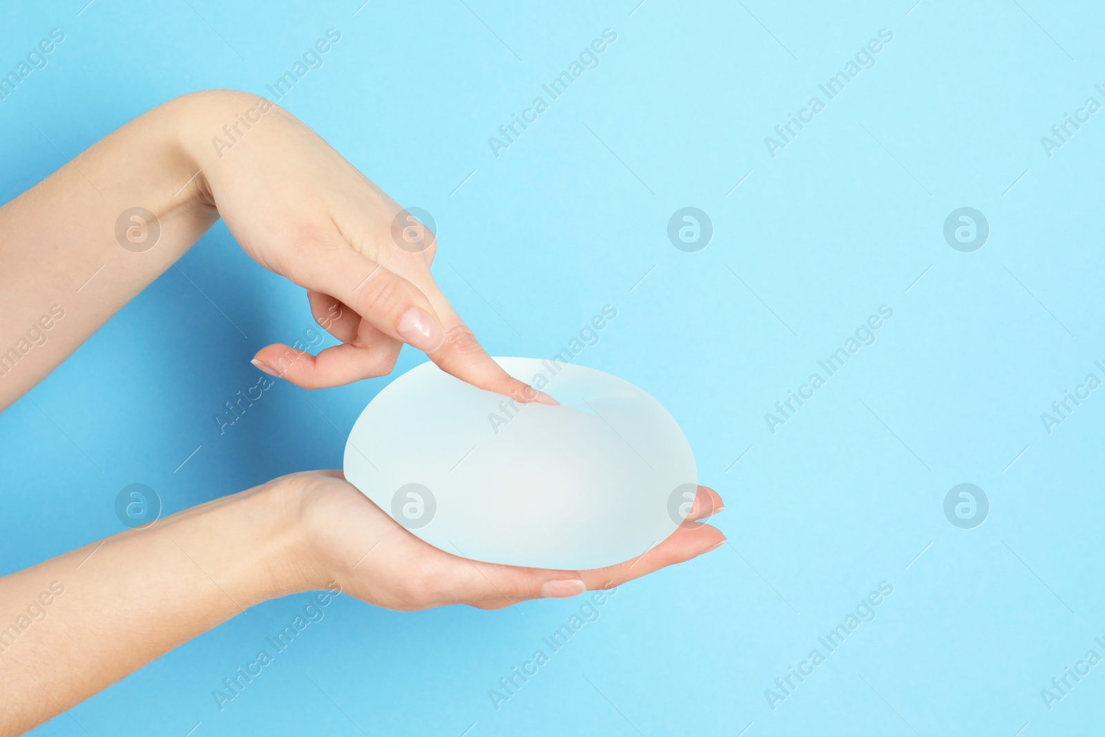 Photo of Woman touching silicone implant for breast augmentation on color background, space for text. Cosmetic surgery