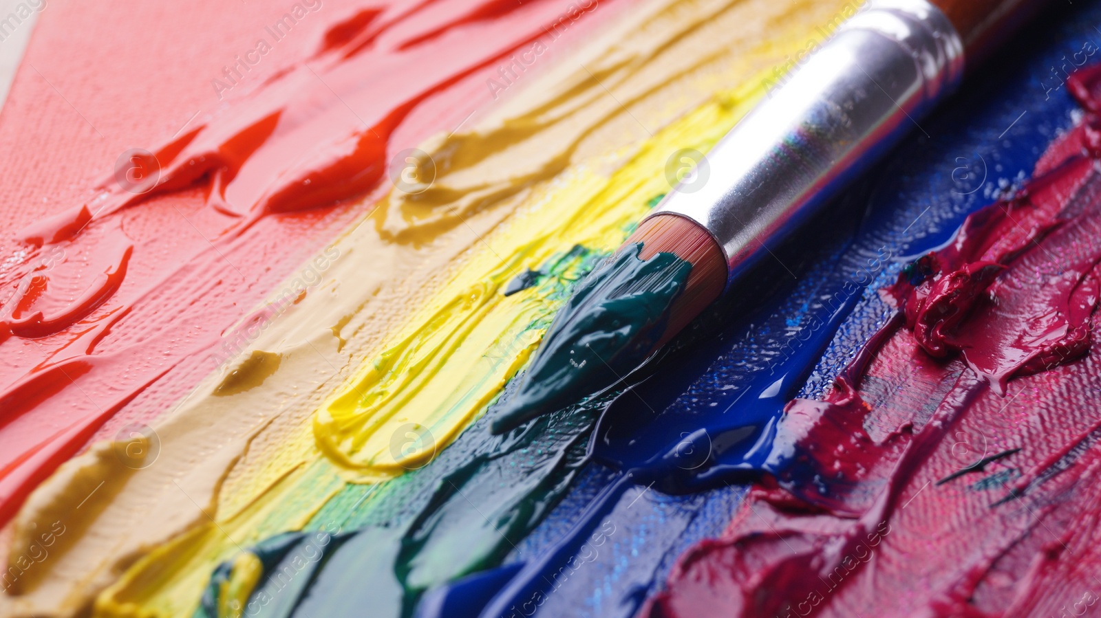 Photo of Brush on artist's palette with colorful mixed paints, closeup