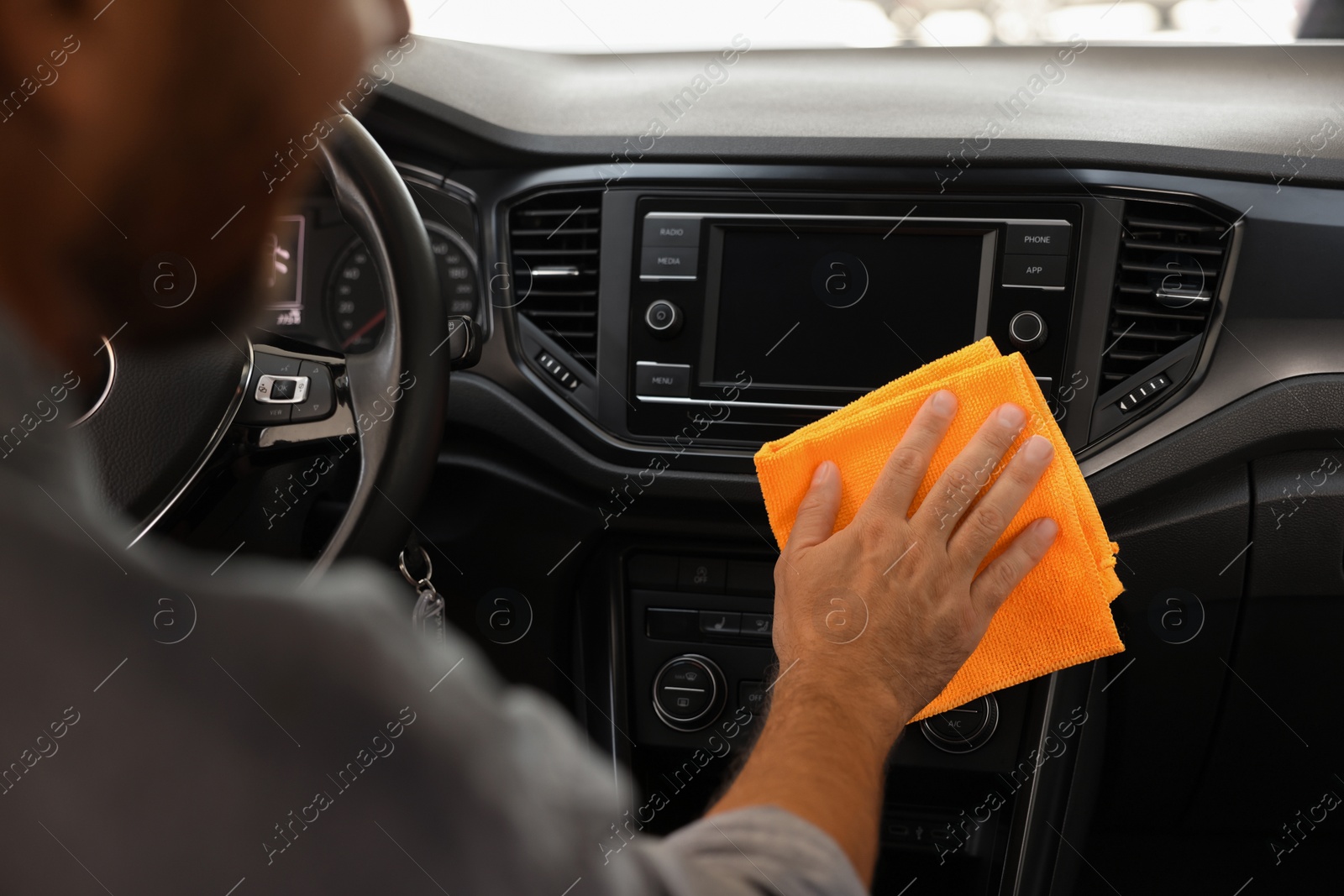 Photo of Man cleaning center console with rag in car, closeup