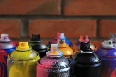 Photo of Used cans of spray paints near brick wall, closeup. Graffiti supplies