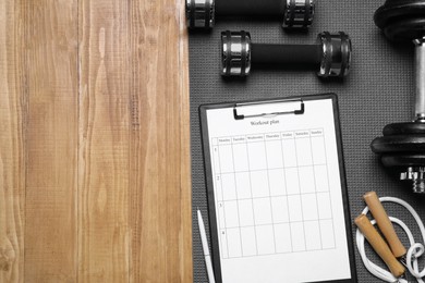 Photo of Personal training. Clipboard with workout plan and sports equipment on wooden table, flat lay. Space for text