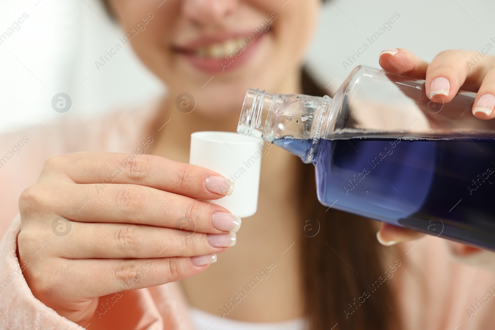 Photo of Young woman using mouthwash on blurred background, closeup