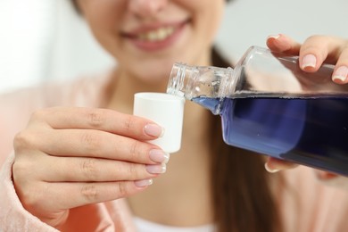 Photo of Young woman using mouthwash on blurred background, closeup