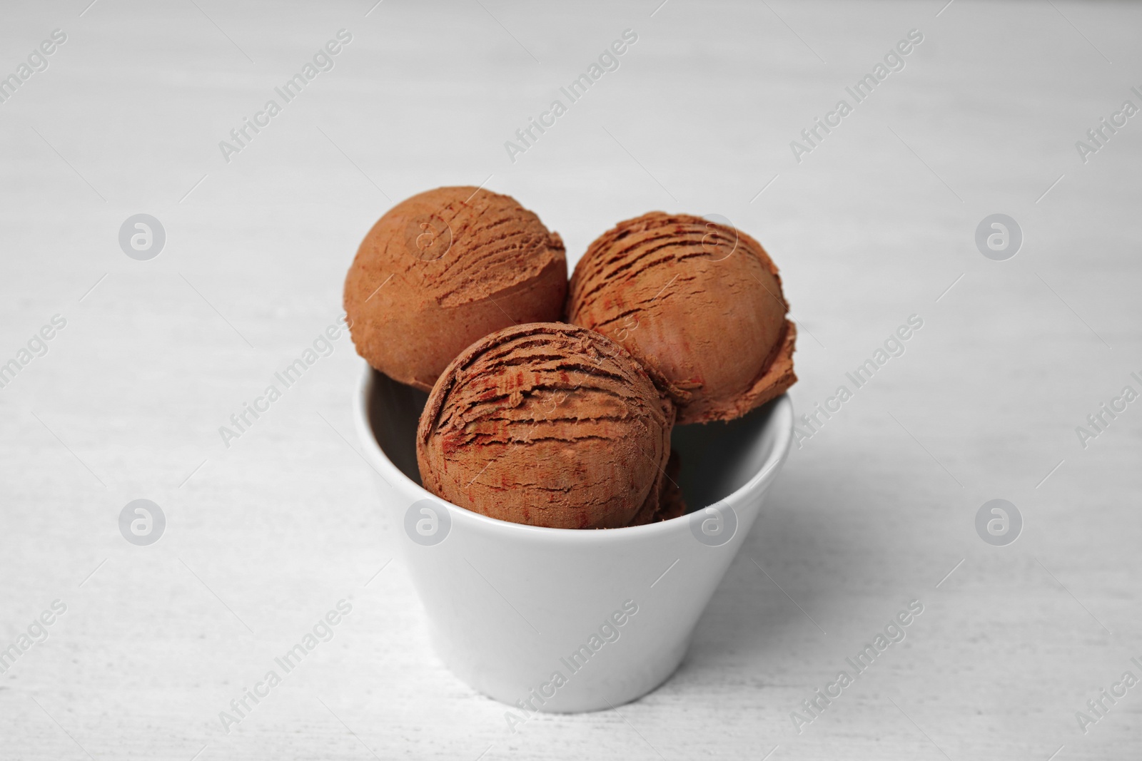 Photo of Bowl of tasty chocolate ice cream on white wooden table