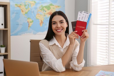 Photo of Travel agent with tickets and passports at table in office
