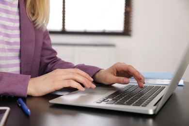 Photo of Young businesswoman using laptop at table in office, closeup