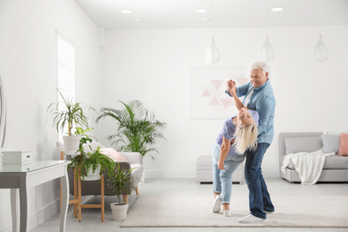 Happy mature couple dancing together in living room