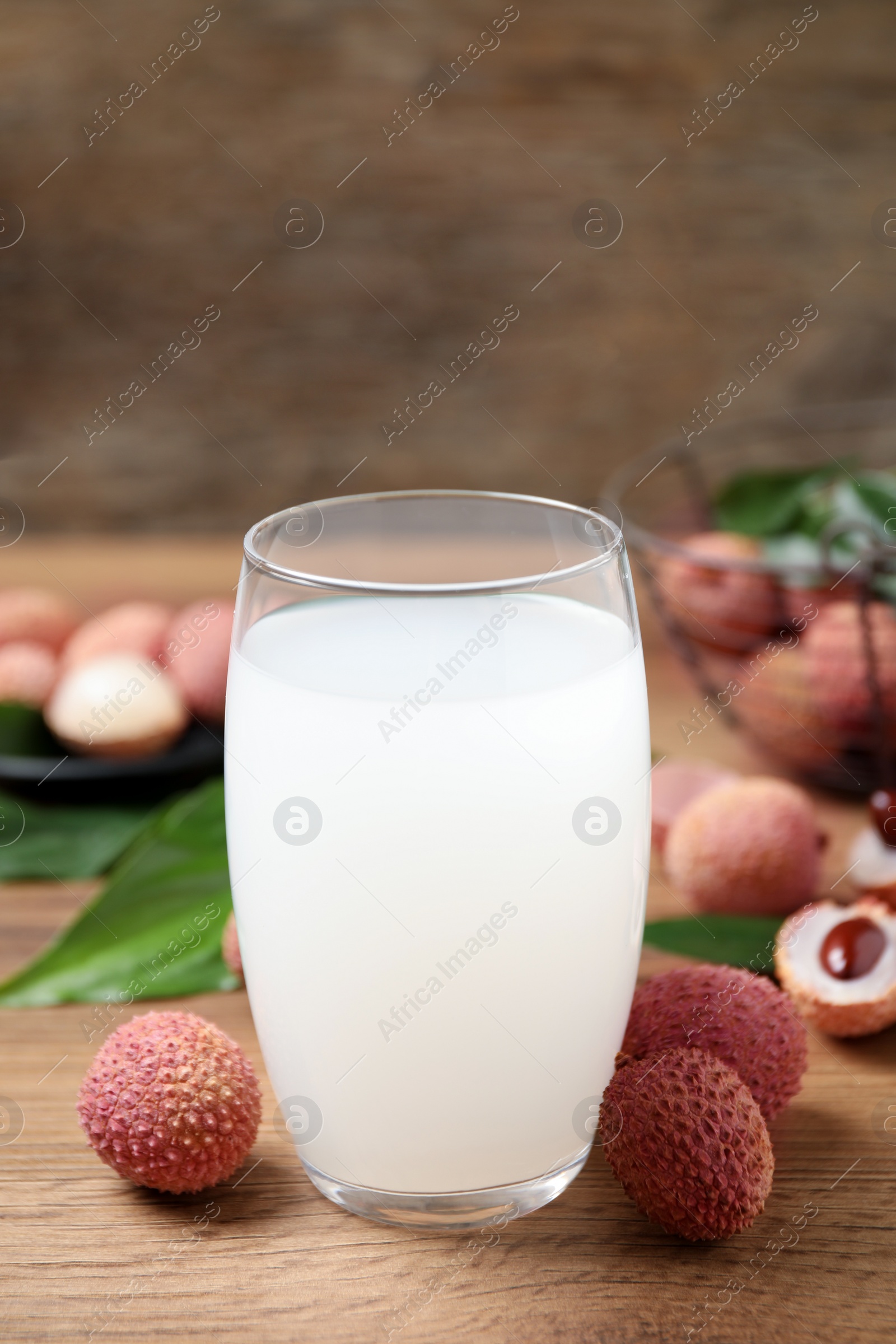 Photo of Lychee juice and fresh fruits on wooden table, closeup