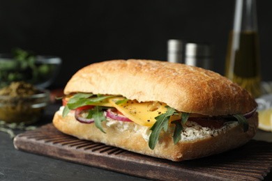 Photo of Delicious sandwich with fresh vegetables and cheese on grey table