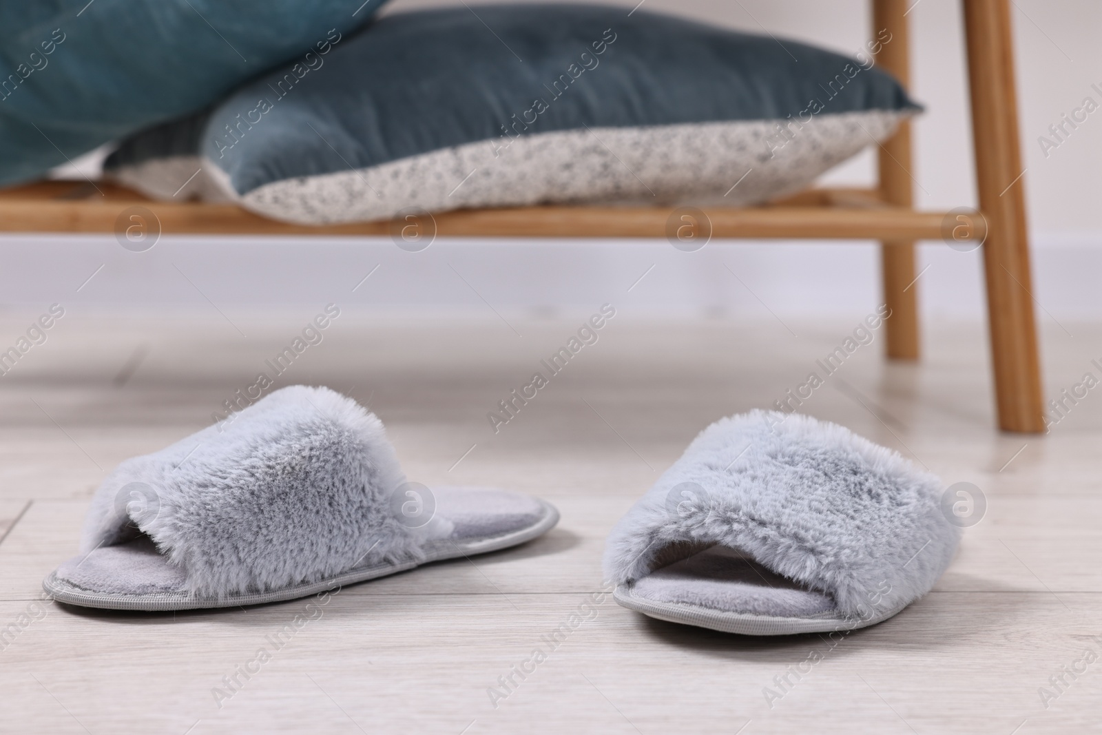 Photo of Grey soft slippers on light wooden floor indoors, closeup