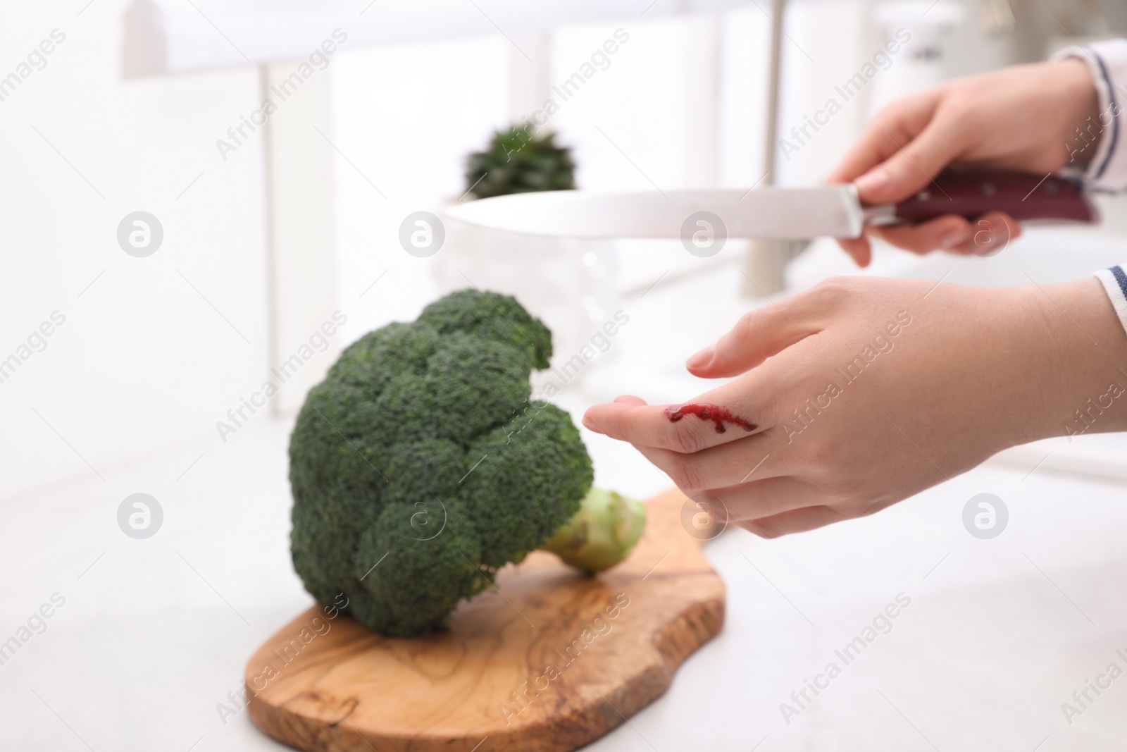 Photo of Woman cut finger while cooking in kitchen, closeup