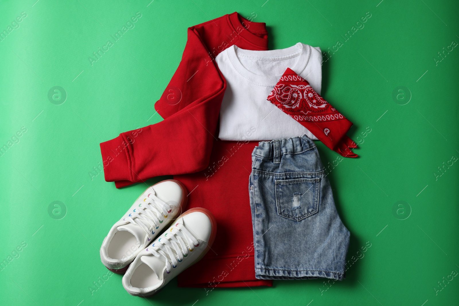 Photo of Stylish child clothes and shoes on green background, flat lay