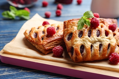 Photo of Fresh delicious puff pastry with sweet berries served on blue wooden table