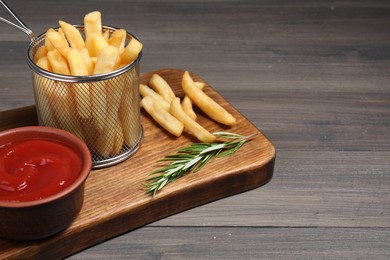 Photo of Delicious French fries served with ketchup on wooden table, space for text