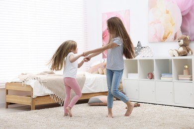 Photo of Cute little sisters having fun together at home