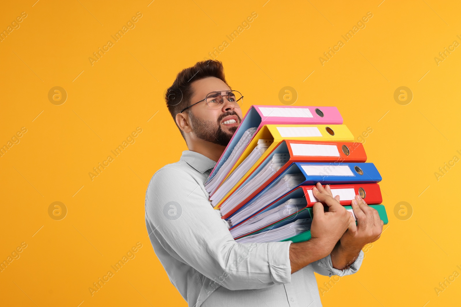 Photo of Stressful man with folders on orange background, space for text