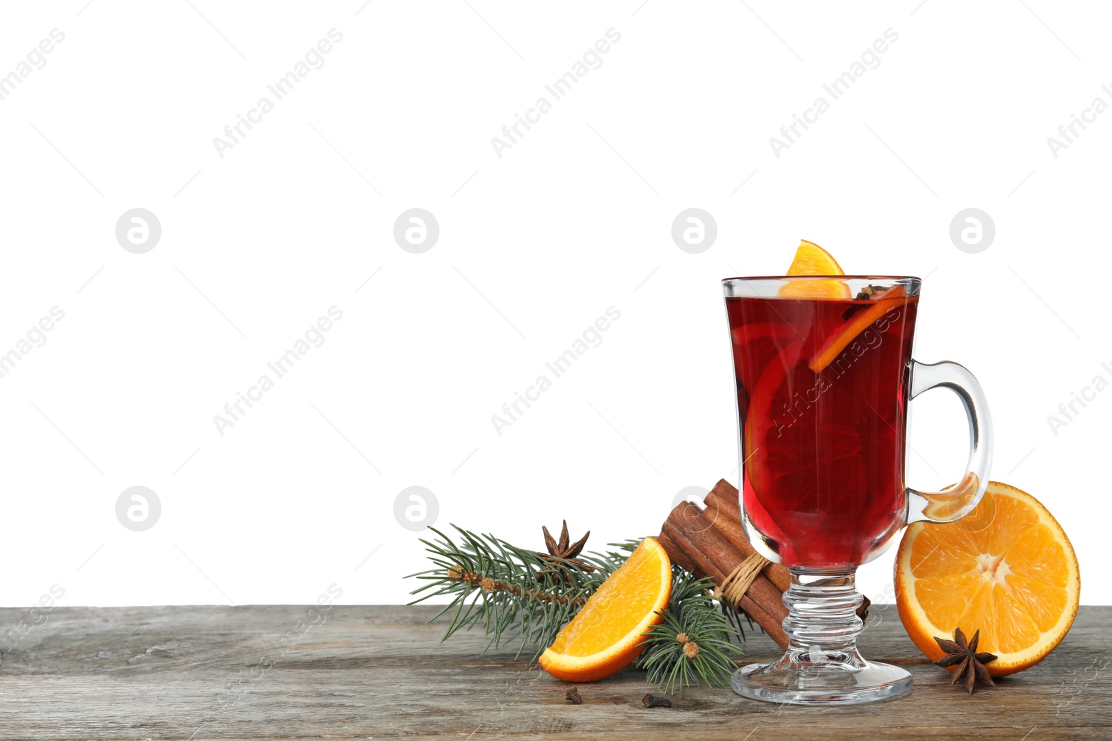 Photo of Composition with glass cup of mulled wine, cinnamon, orange and fir branch on table against white background. Space for text