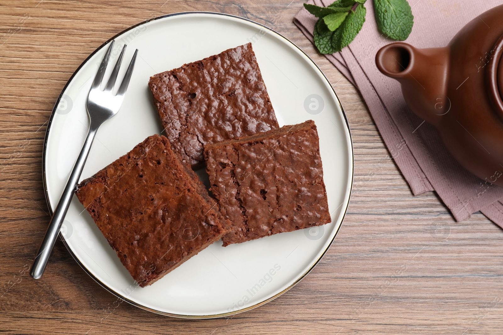 Photo of Delicious chocolate brownies served on wooden table, flat lay