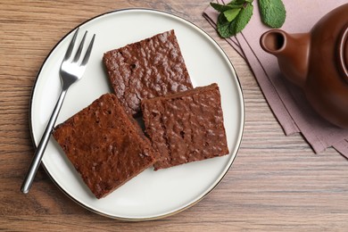 Delicious chocolate brownies served on wooden table, flat lay