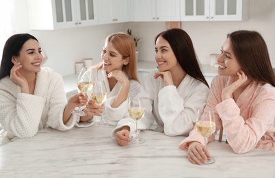 Photo of Beautiful young ladies with glasses of wine in kitchen. Women's Day