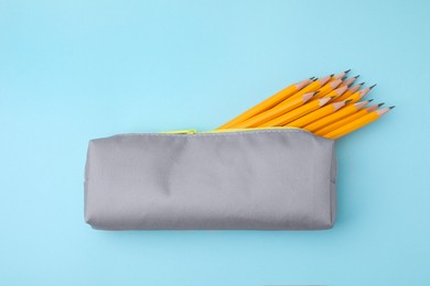 Many sharp pencils in pencil case on light blue background, top view