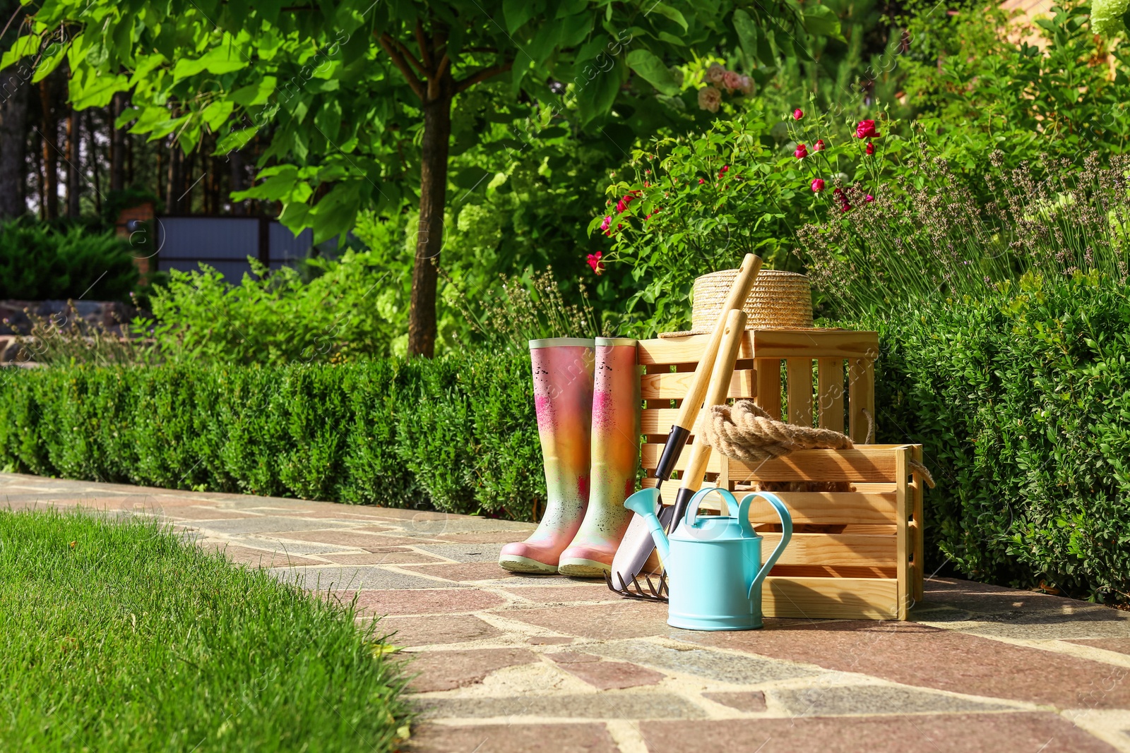 Photo of Wooden crates and gardening tools on stone path at backyard