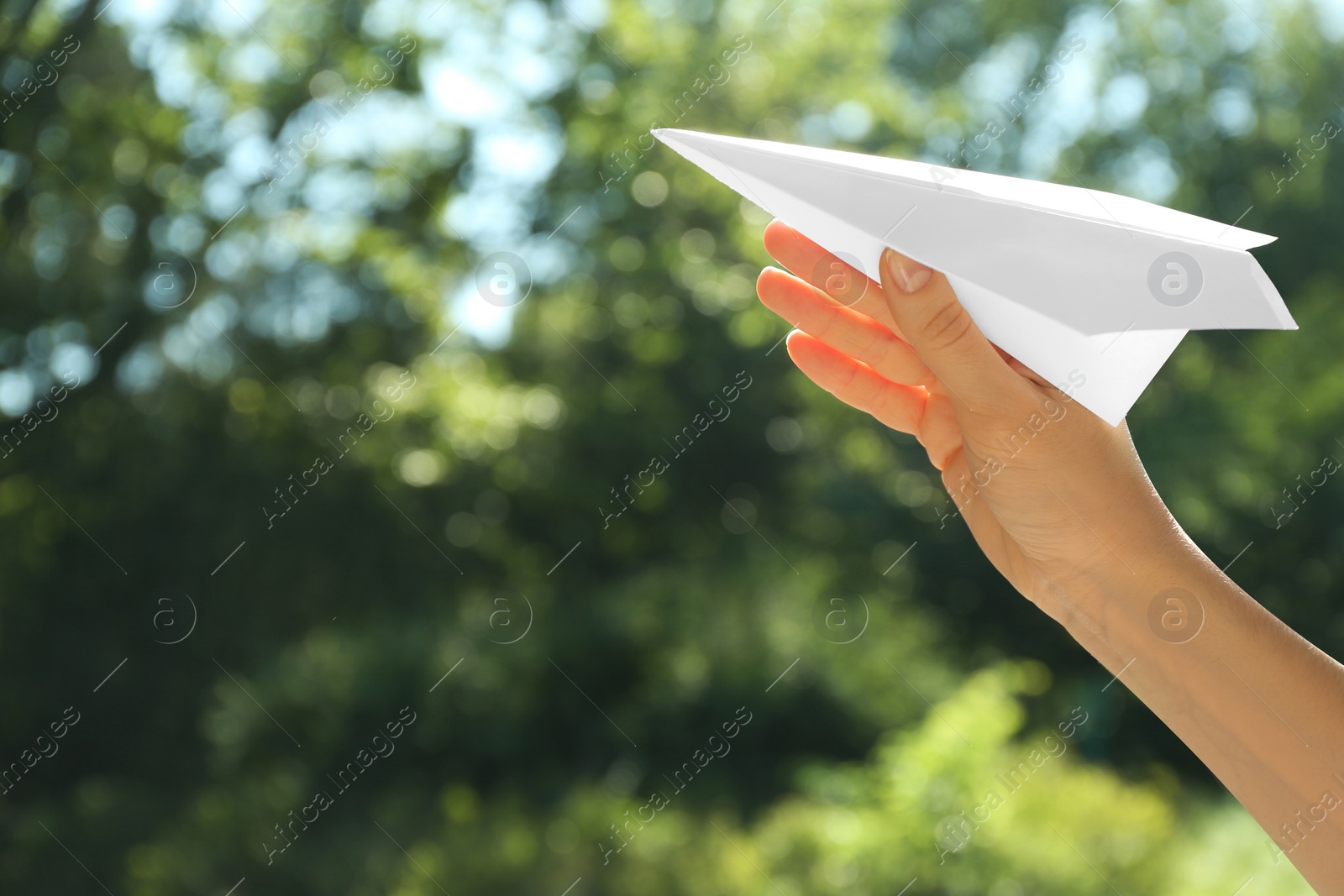 Photo of Woman holding paper plane outdoors, closeup. Space for text