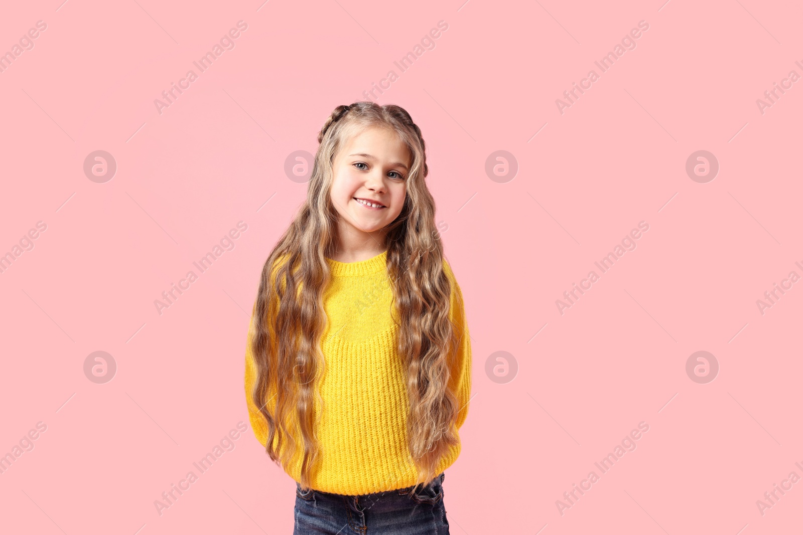 Photo of Cute little girl with braided hair on pink background