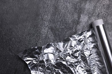 Photo of Roll of aluminum foil on grey table, top view. Space for text